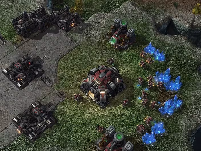 A screenshot from StarCraft II showing a Terran base with buildings and worker units. The units are gathering resources from blue mineral fields, illustrating an environment where an AI's reward can be based on collecting different types of resources.