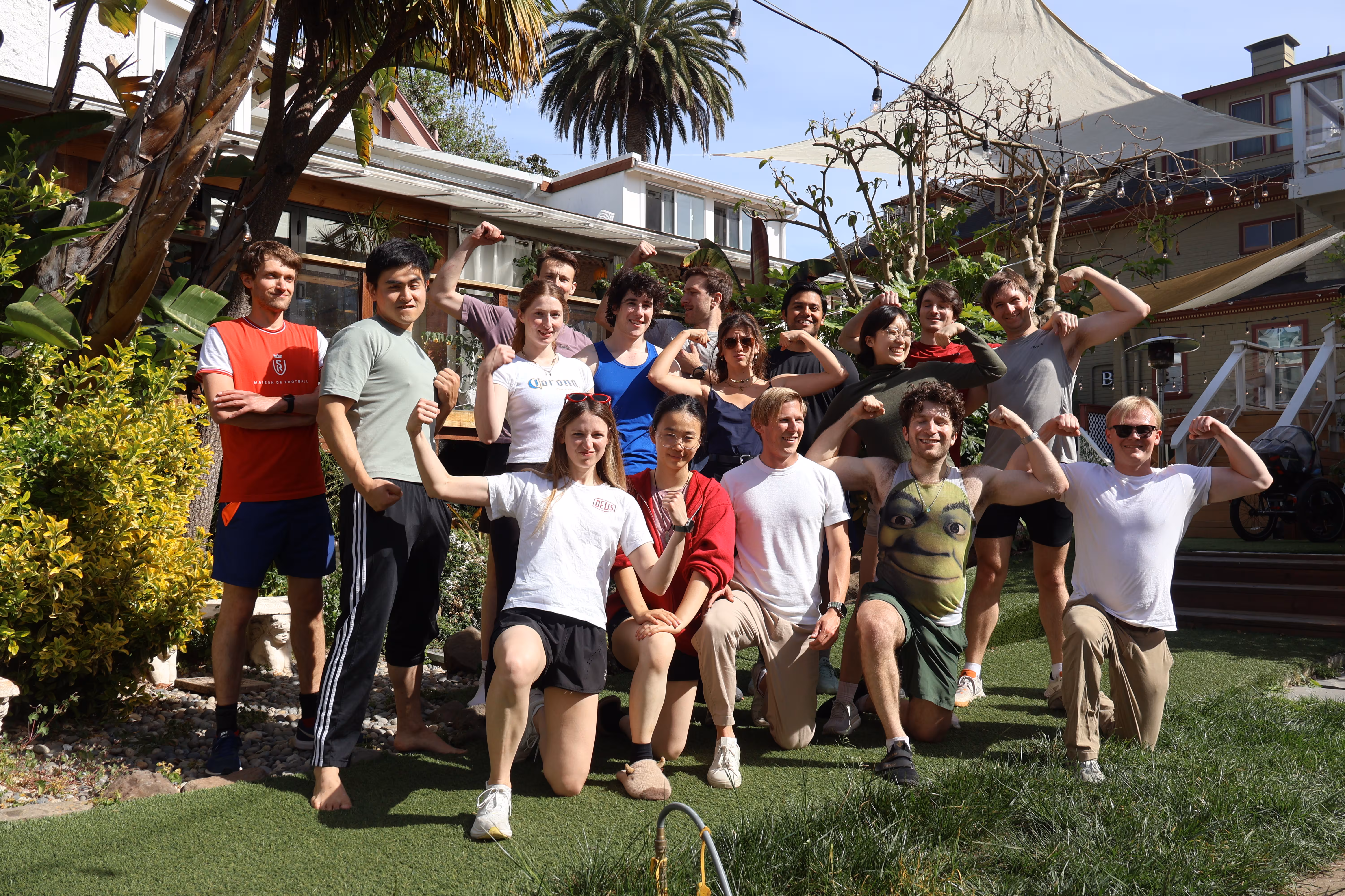 Sixteen people happily flex for the camera. Alex wears a Shrek tank top.