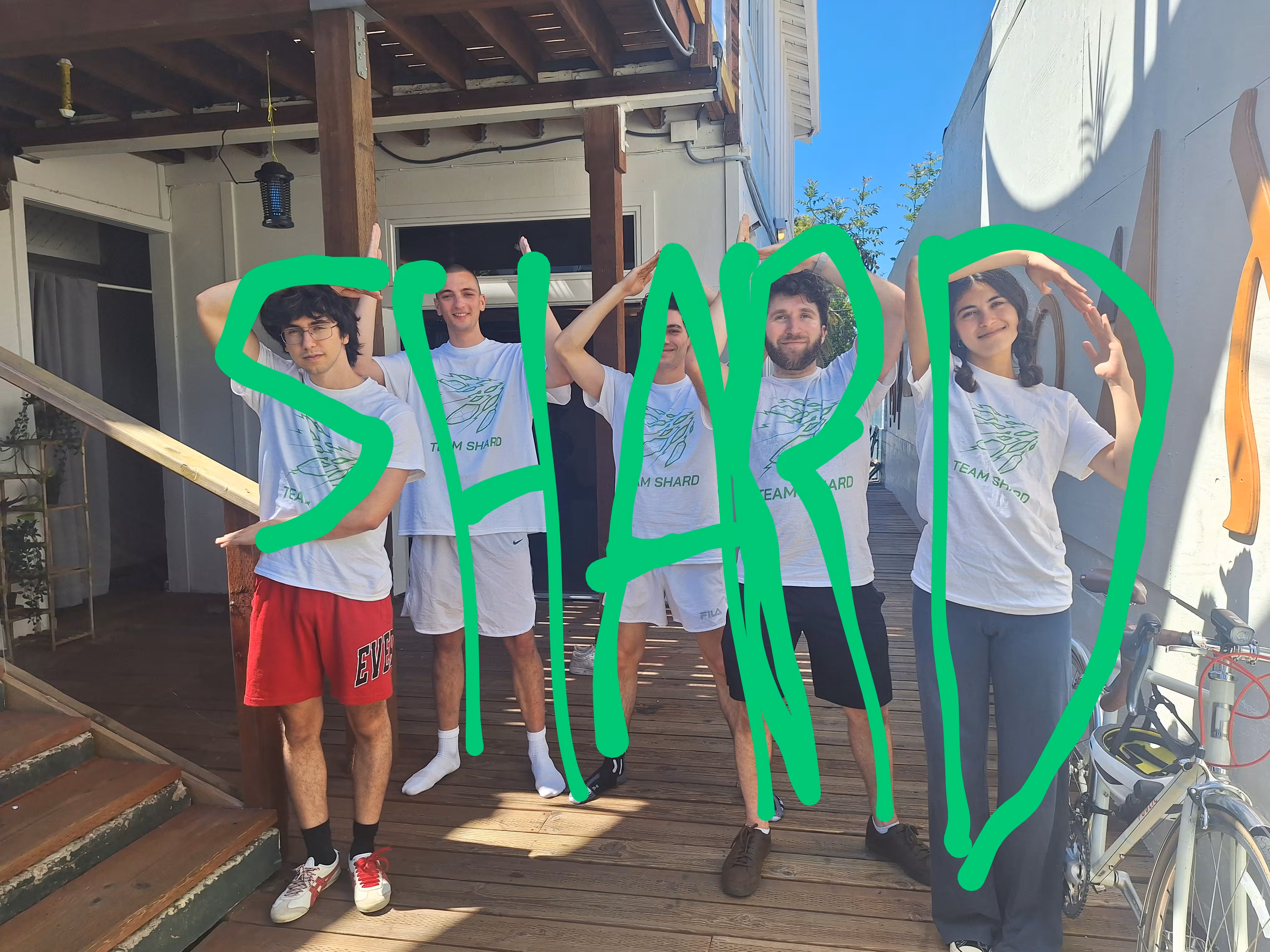 Five people outside of a gym loosely spell "S H A R D" with their poses, with green lettering drawn over each person.
